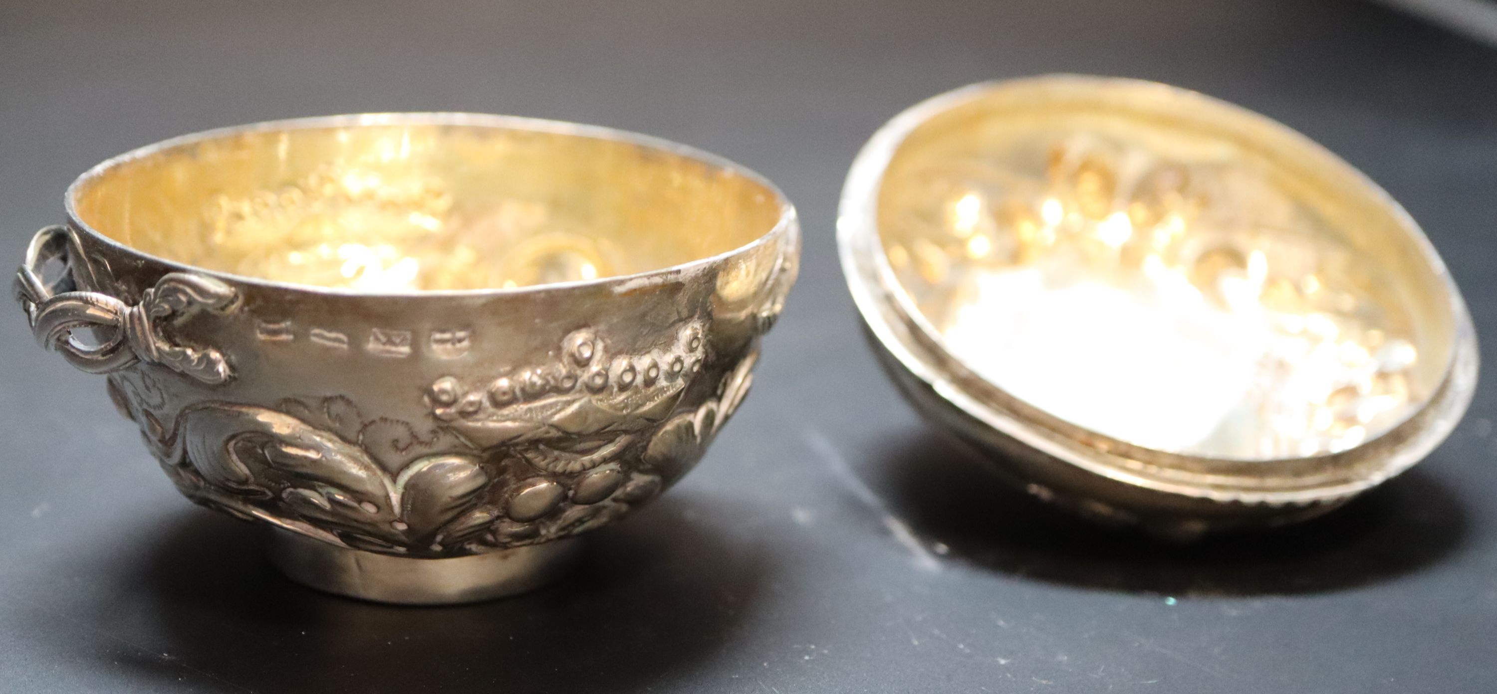 A 19th century Continental circular embossed white metal two handled pot and cover, 83mm, 99 grams. (a.f.)
